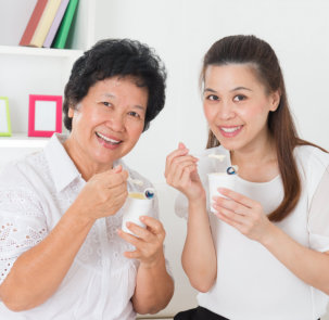 photo of a senior woman eating yogurt with her caregiver