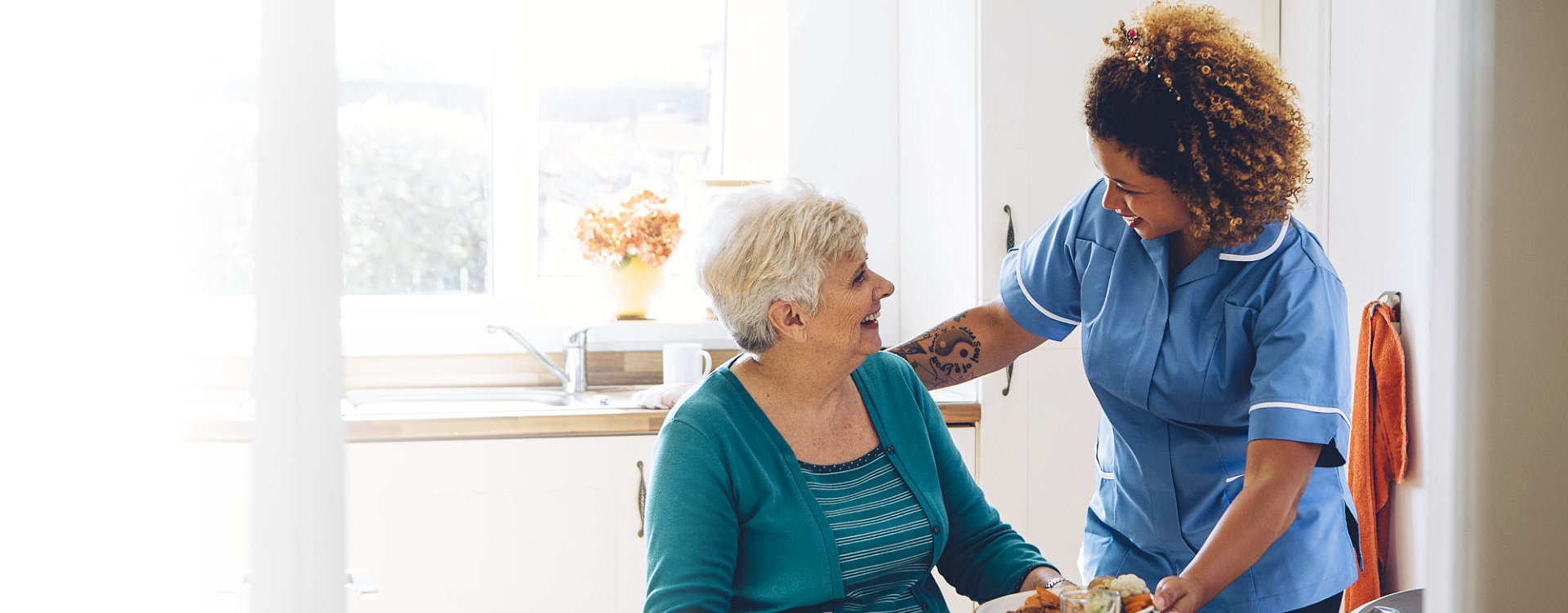 caregiver serving food to a senior woman