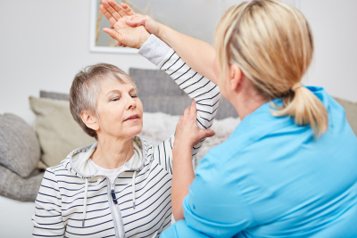 nurse helping senior raise her left hand