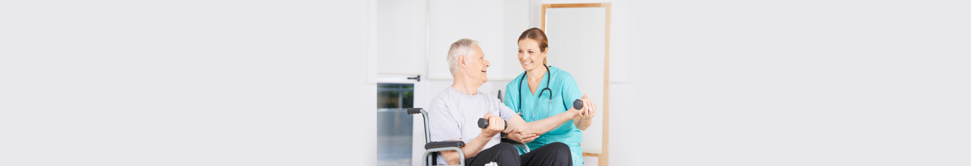 senior man raising a dumbbell while the caregiver assisting to him